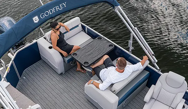 couple relaxing at the stern table on a godfrey sweetwater entertainment pontoon