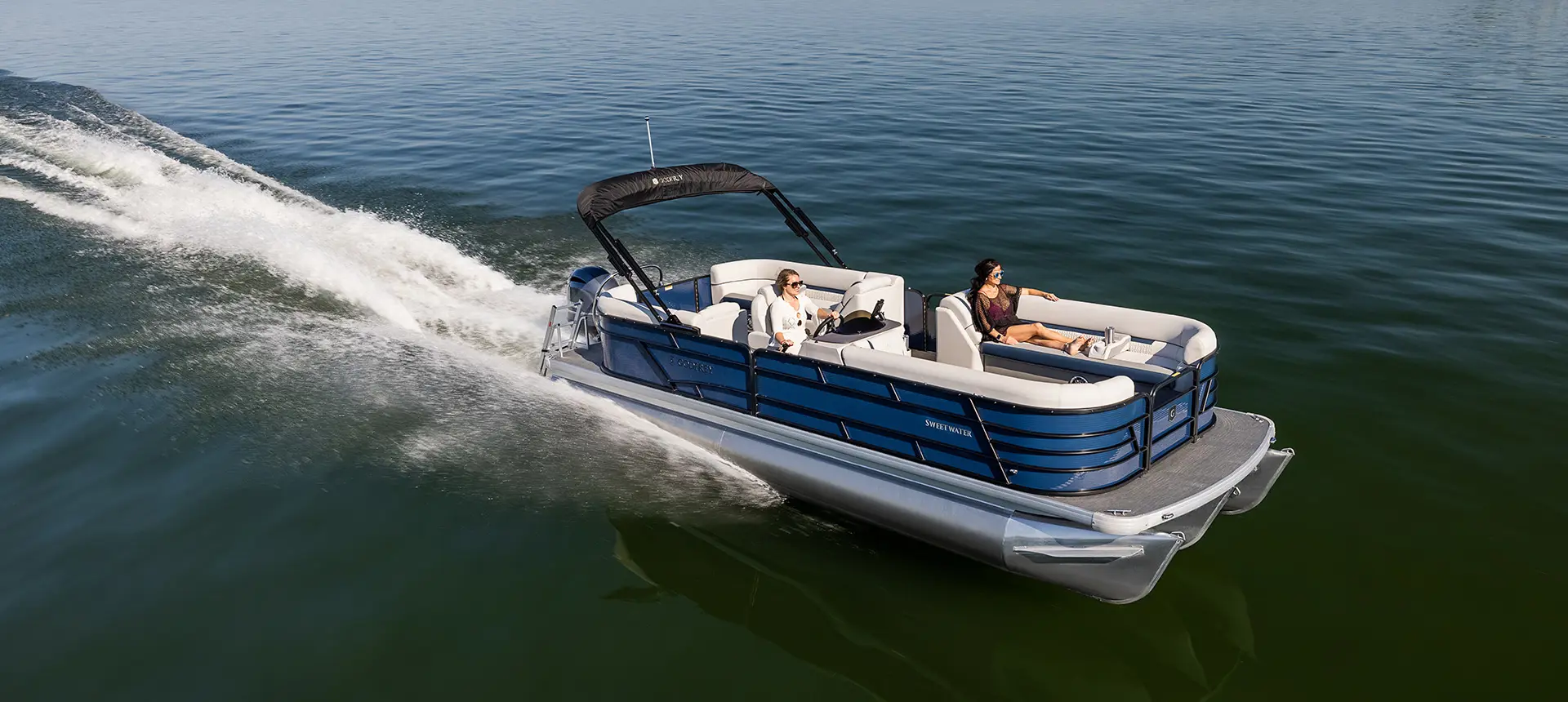 2 femmes sur un ponton godfrey sweetwater split bench naviguant en vitesse sur un lac