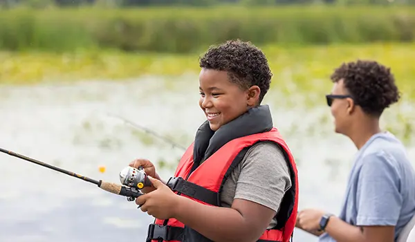 garçons souriants qui pêchent sur un ponton godfrey xperience fishing