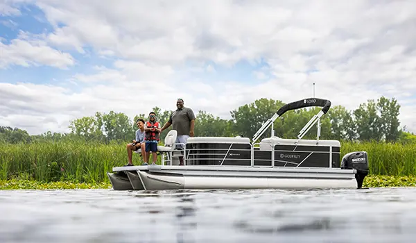 papa pointant à ses fils un point de pêche sur la proue d’un ponton godfrey xperience fishing