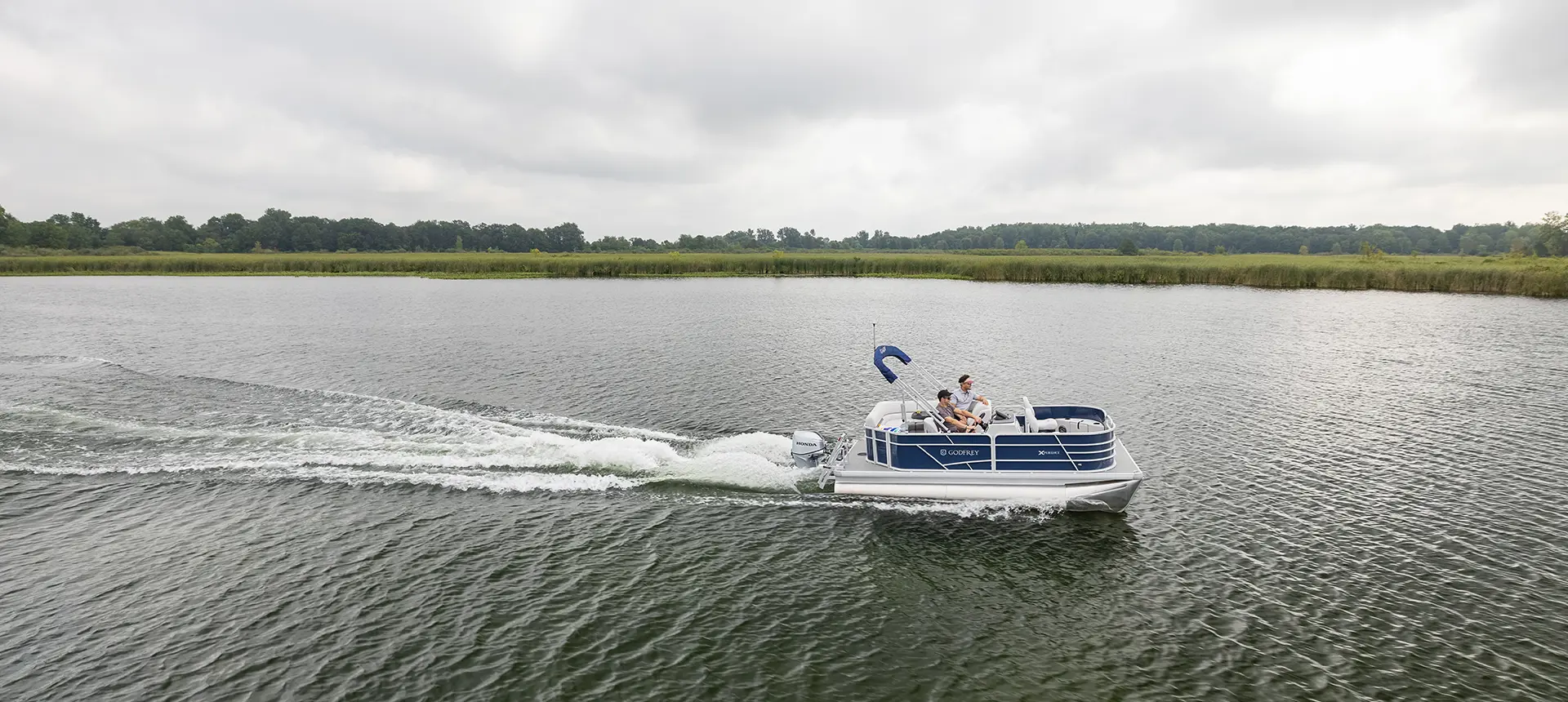 vue de profil d’un ponton godfrey xperience fishing naviguant sur un lac