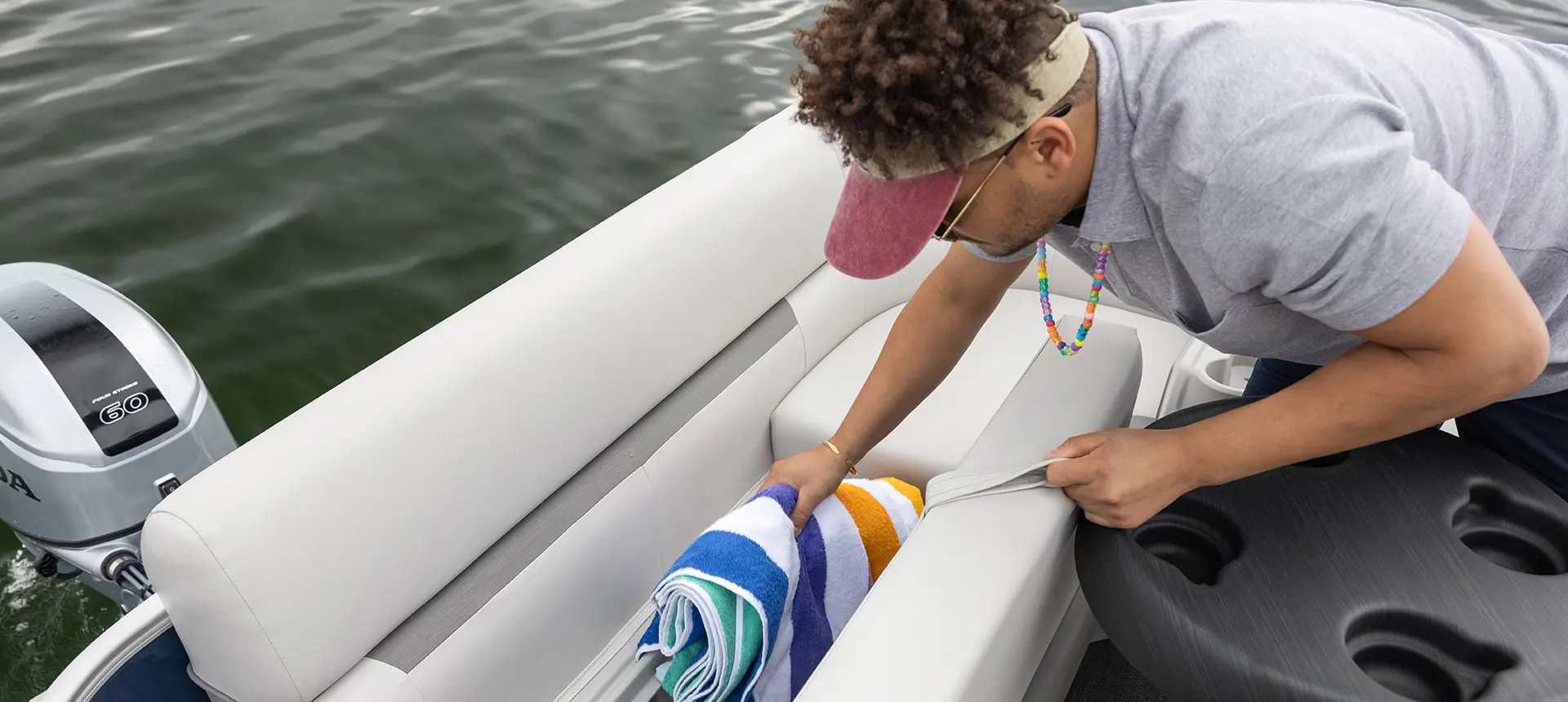 homme sortant une serviette du rangement sous le siège d’un ponton godfrey xperience fishing