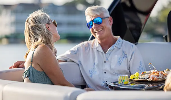 Couple se souriant à bord d’un ponton Godfrey Sanpan Lounge 2700 ULW Twin.