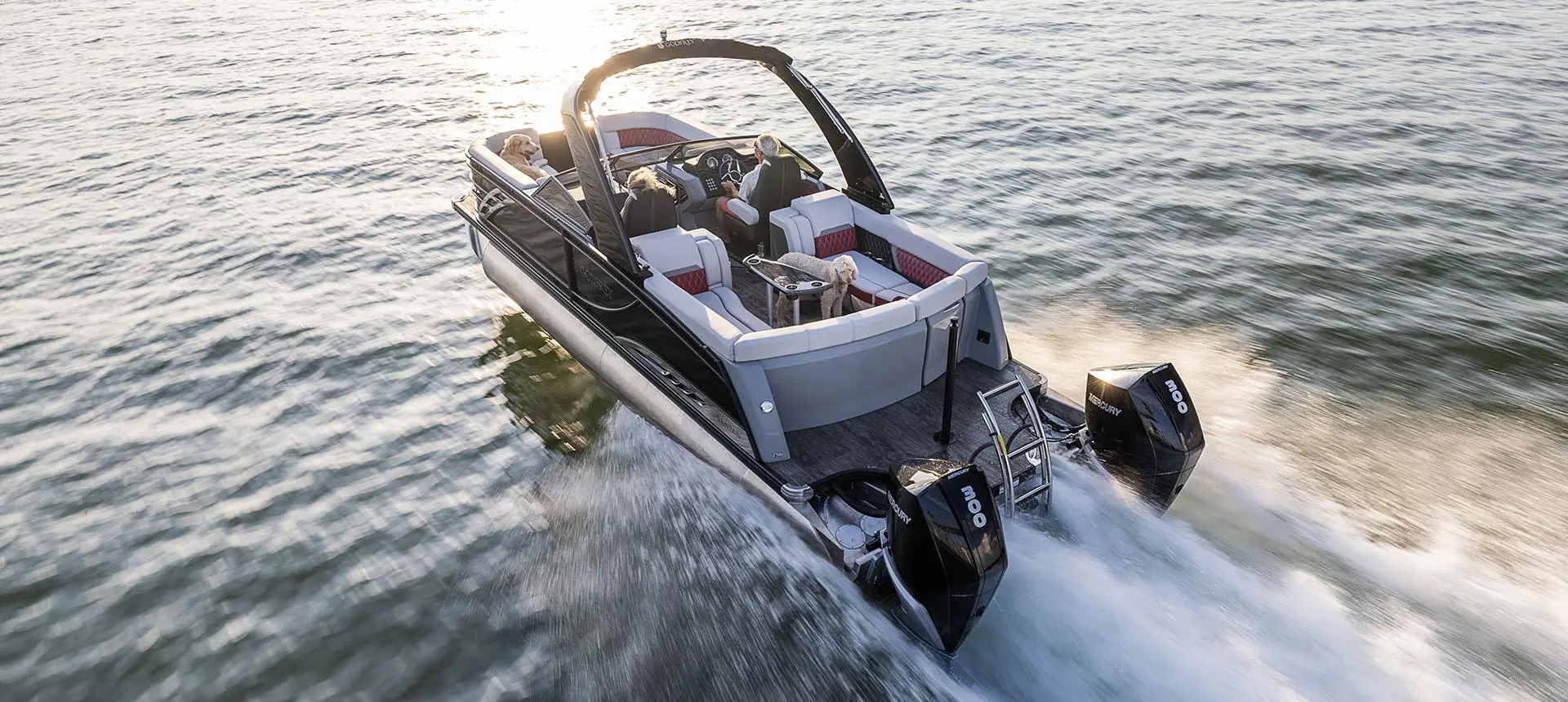 Vue de la poupe d’un ponton Godfrey Sanpan Lounge 2700 ULW Twin traversant un lac à toute vitesse.