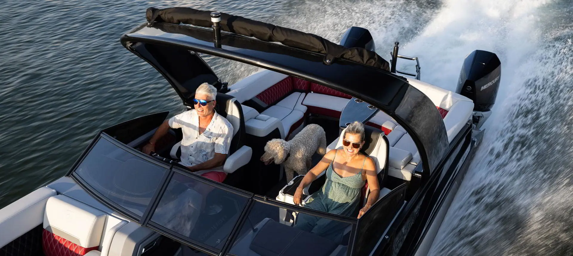 Couple avec leurs chiens souriant dans un bateau ponton Godfrey Sanpan Lounge 2700 ULW Twin.