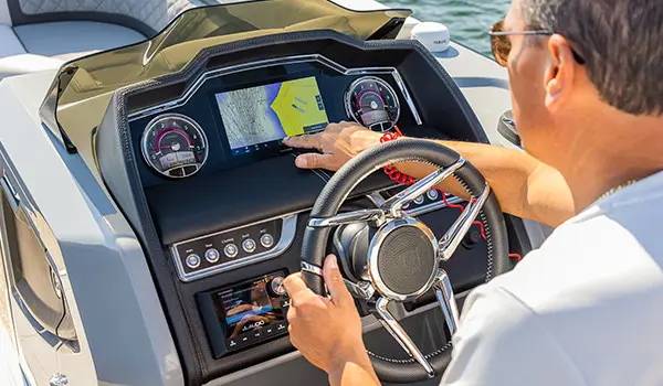 man pointing to garmin gps on the helm dashboard on a godfrey aquapatio series pontoon