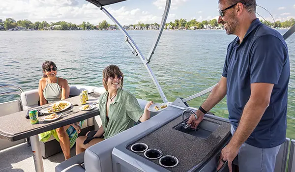 woman handing a dirty plan to a man standing at the sink on a godfrey aquapatio series pontoon