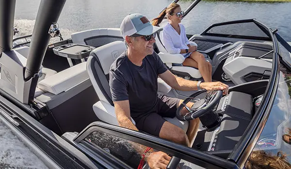 man sitting at the helm on a godfrey aquapatio series pontoon
