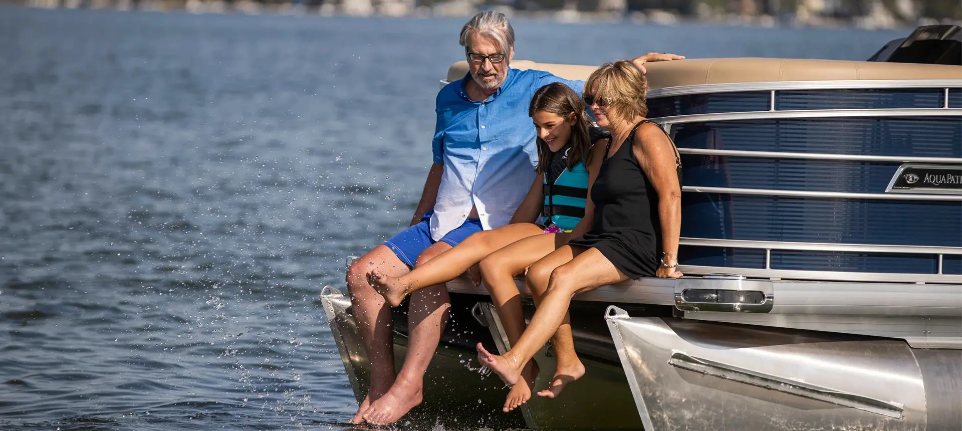 family sitting on the bow of a godfrey aquapatio series pontoon