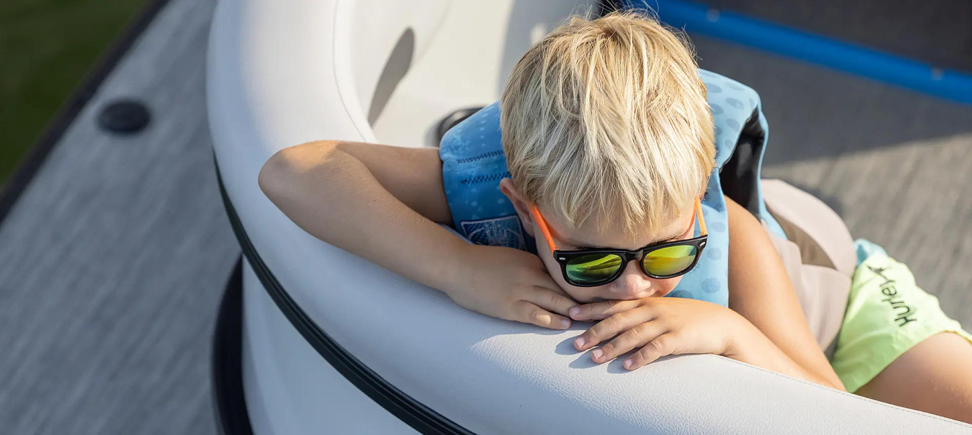 boy with sunglasses relaxing on the bow of a godfrey mighty g pontoon