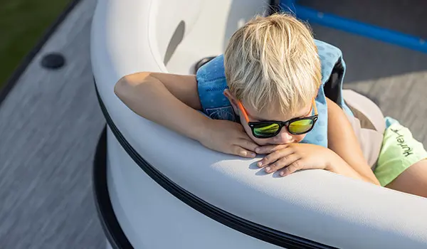 boy with sunglasses relaxing on the bow of a godfrey mighty g pontoon