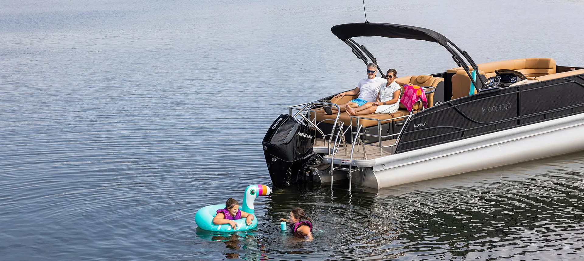 parents watching their kids swimming near their godfrey monaco series pontoon