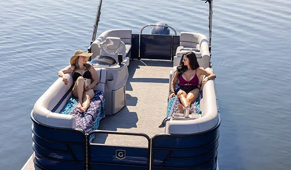 2 women relaxing on a the bow of a godfrey sweetwater pontoon