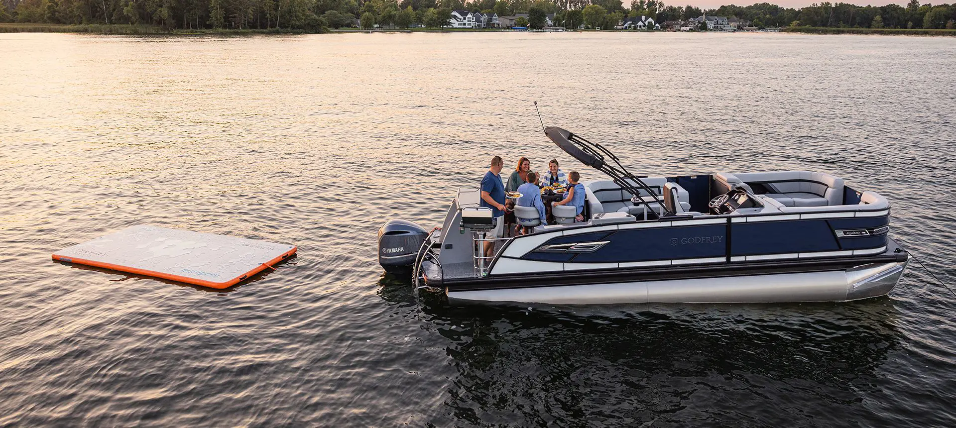 Family having a snack on the stern table on a Godfrey AquaPatio Entertainment pontoon boat.