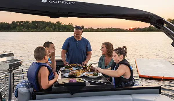family eating at the stern table on a godfrey aquapatio entertainment pontoon