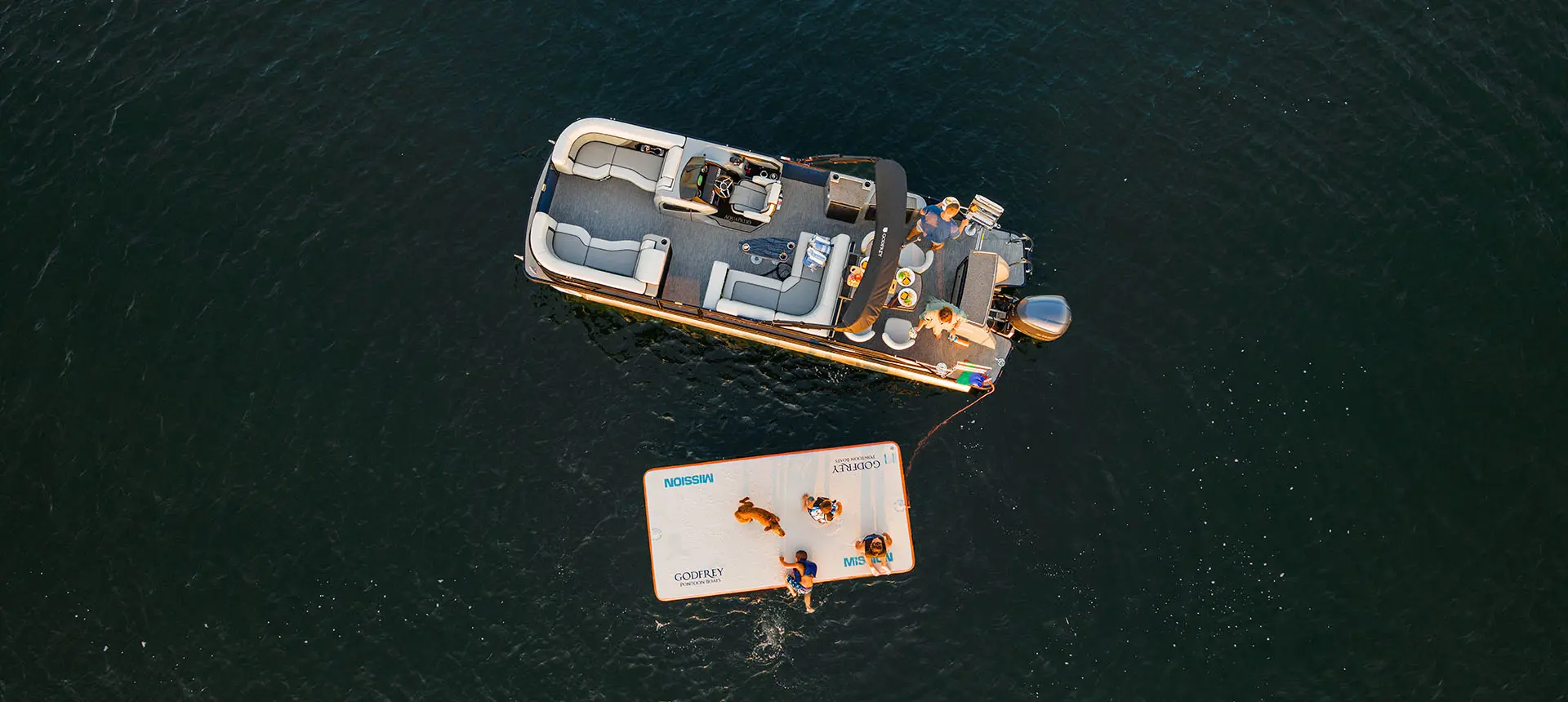 family riding on a godfrey aquapatio series pontoon across a lake