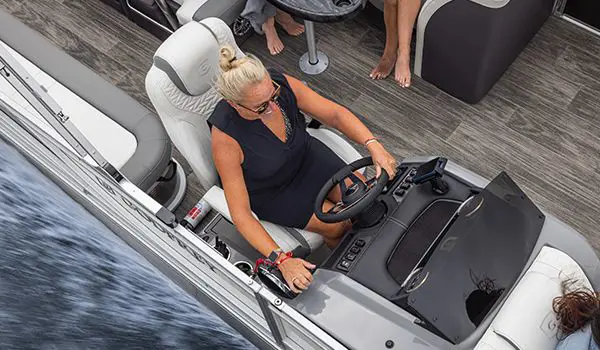 woman sitting at the steering console on a godfrey monaco lounge pontoon