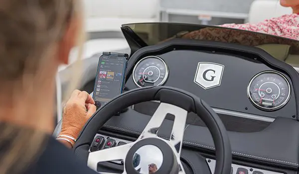 woman using her phone at the helm of a godfrey monaco lounge pontoon