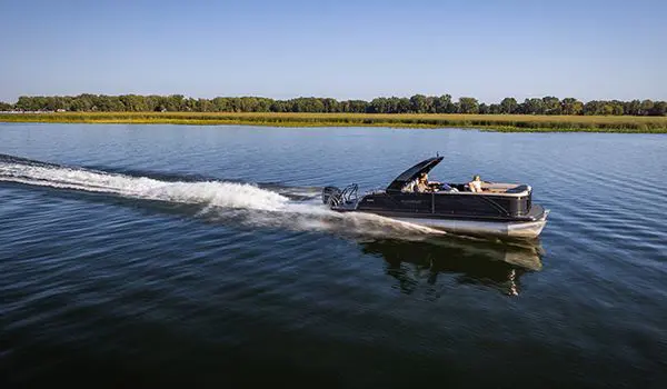 side profile of a godfrey monaco lounge pontoon cruising on a lake