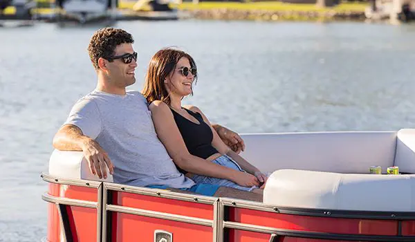 couple relaxing on the bow split bench seats on a godfrey sweetwater entertainment pontoon