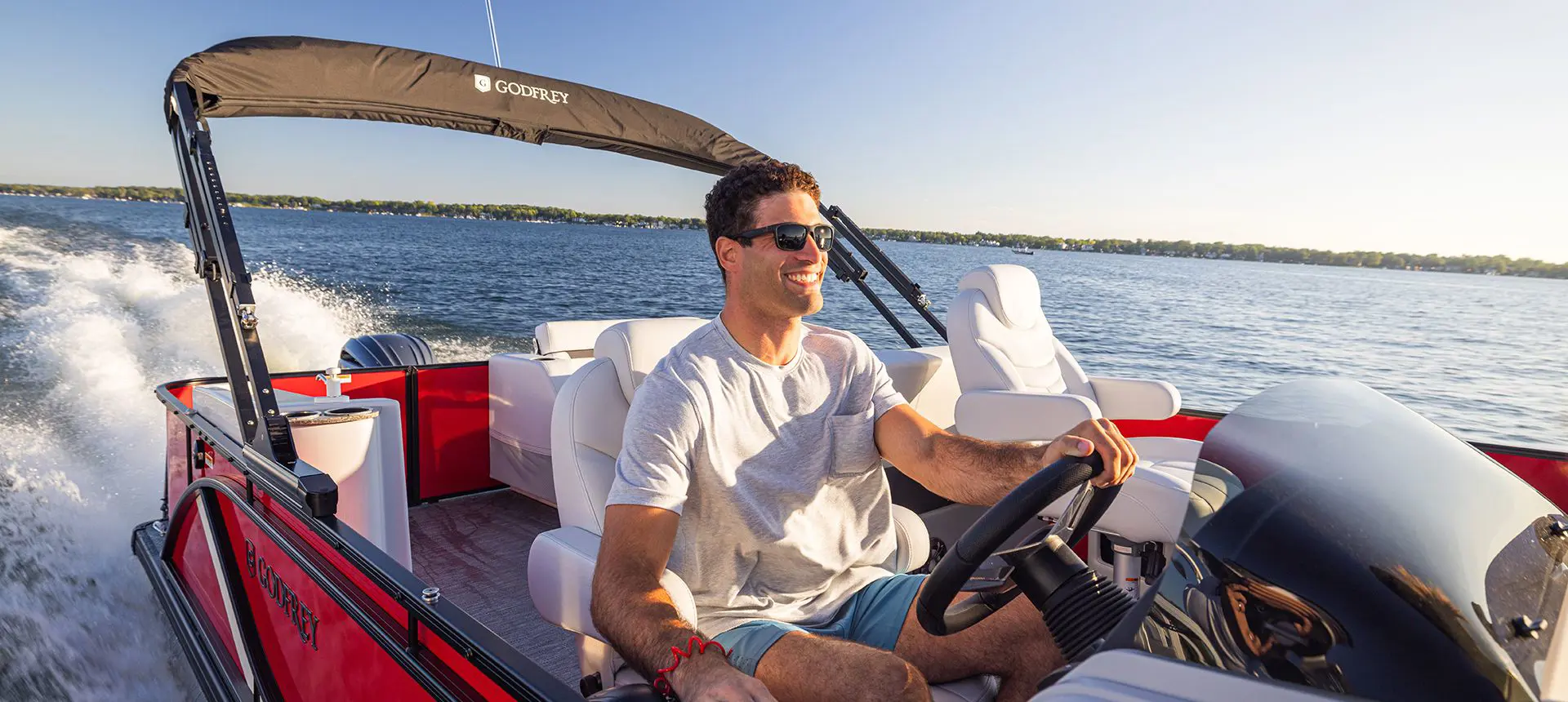 man sitting at the steering console of a godfrey sweetwater entertainment pontoon