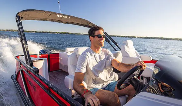 man sitting at the steering console of a godfrey sweetwater entertainment pontoon