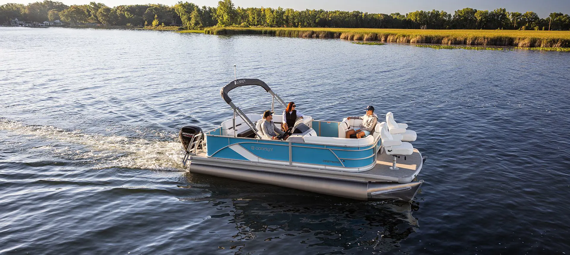 side view of a godfrey sweetwater fishing pontoon cruising across a lake
