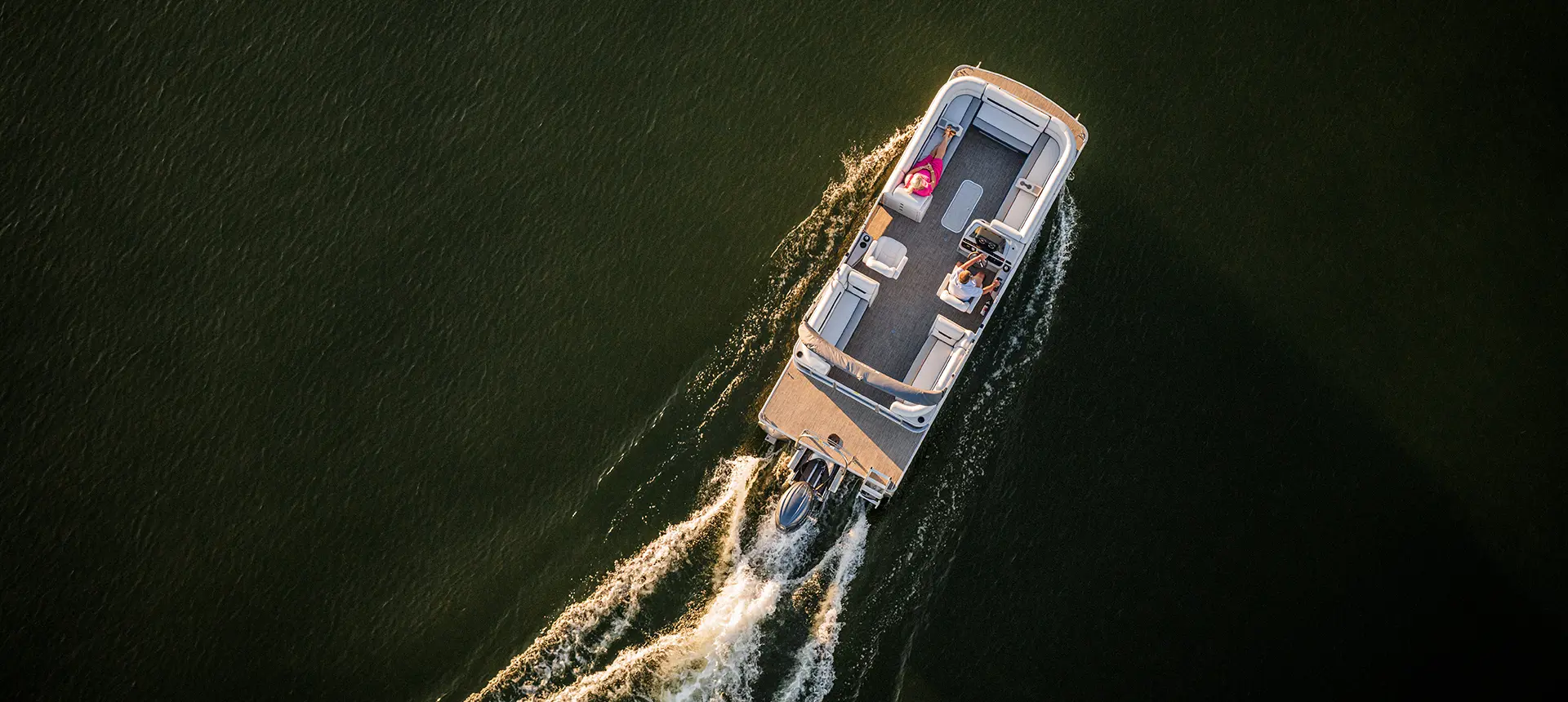aerial view of a woman relaxing on the bow split bench seat on a godfrey sweetwater split bench pontoon