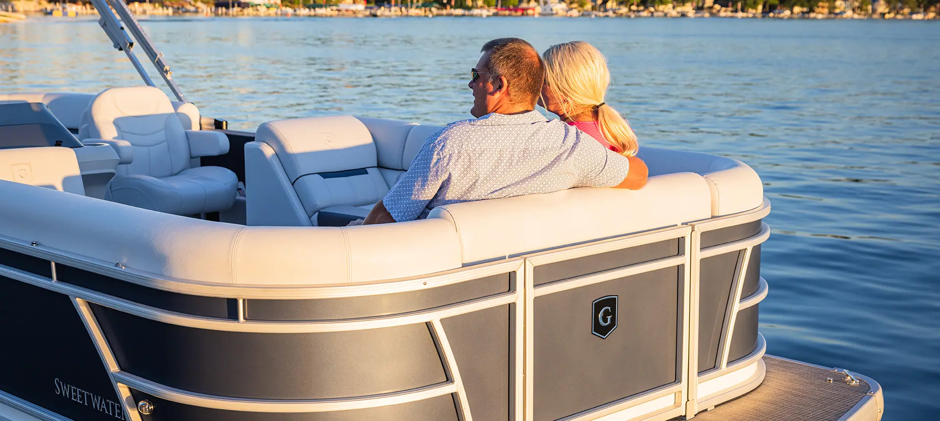 couple relaxing on the bow of a godfrey sweetwater split bench pontoon