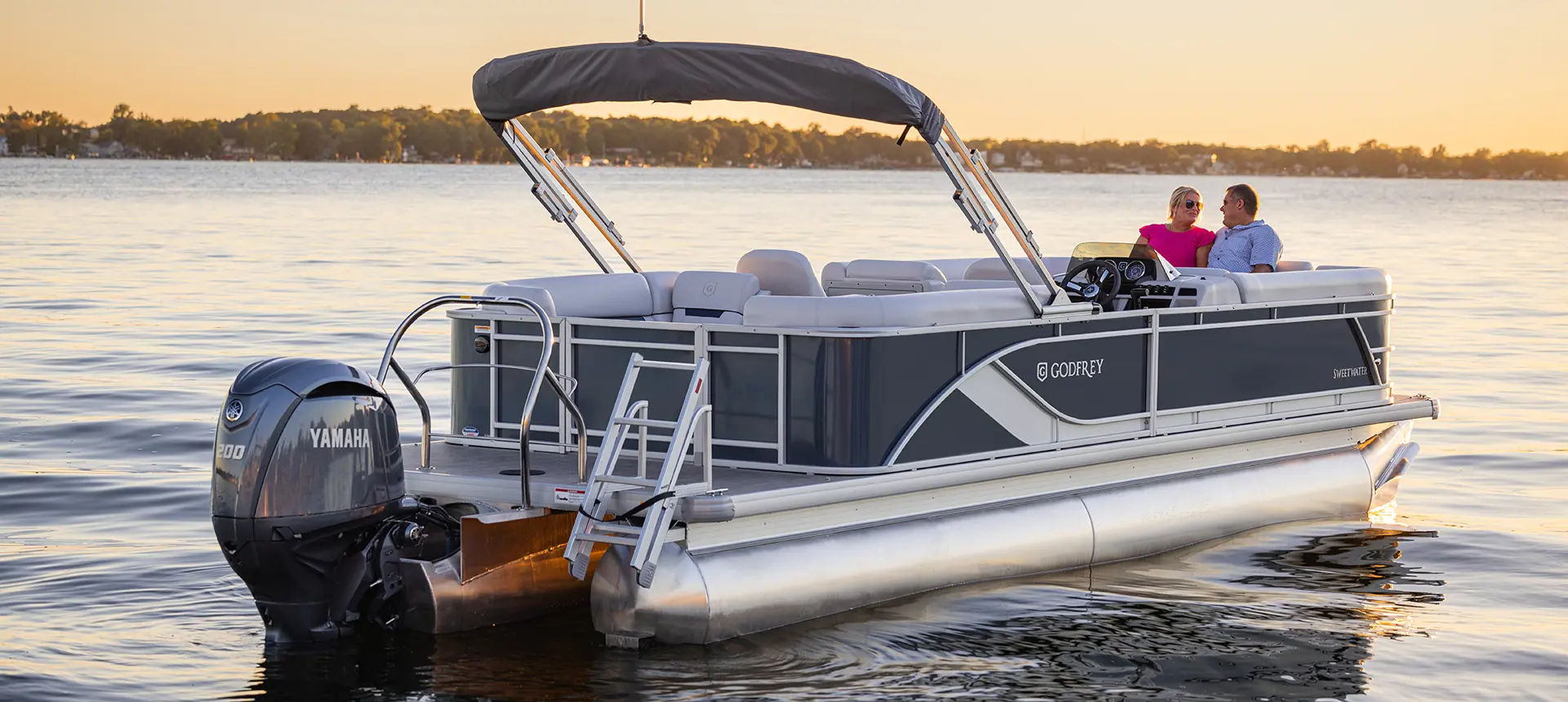 couple looking at each other on the bow of a godfrey sweetwater split bench pontoon