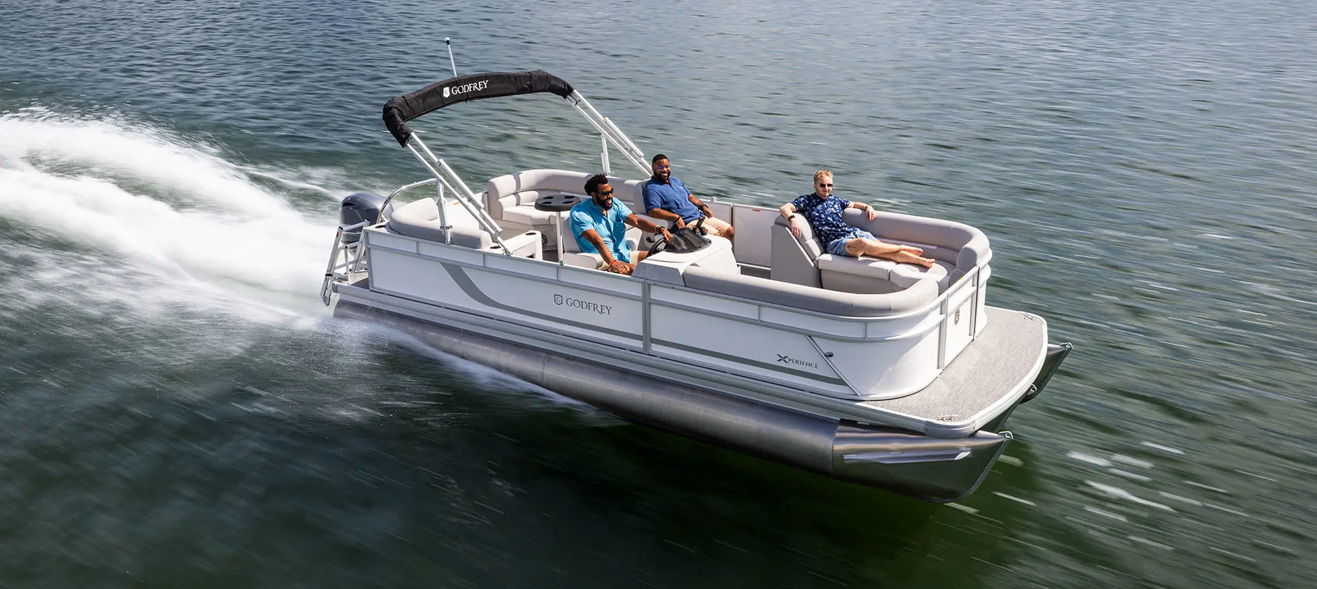 side view of a godfrey xperience split bench pontoon cruising on a lake