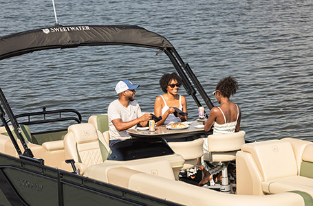 3 people eating at the midship table on a Godfrey pontoon boat with the Entertainment layout.
