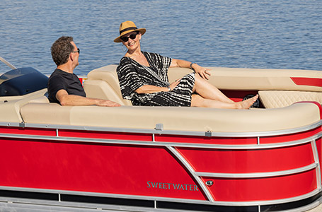 A couple smiling at each other about the premium style featured on a Godfrey pontoon boat with a Split Bench layout.