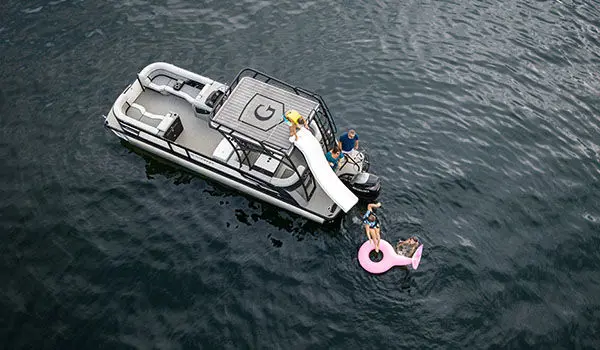 Aerial view of a kid going down the slide on a Godfrey AquaPatio Entertainment pontoon boat.