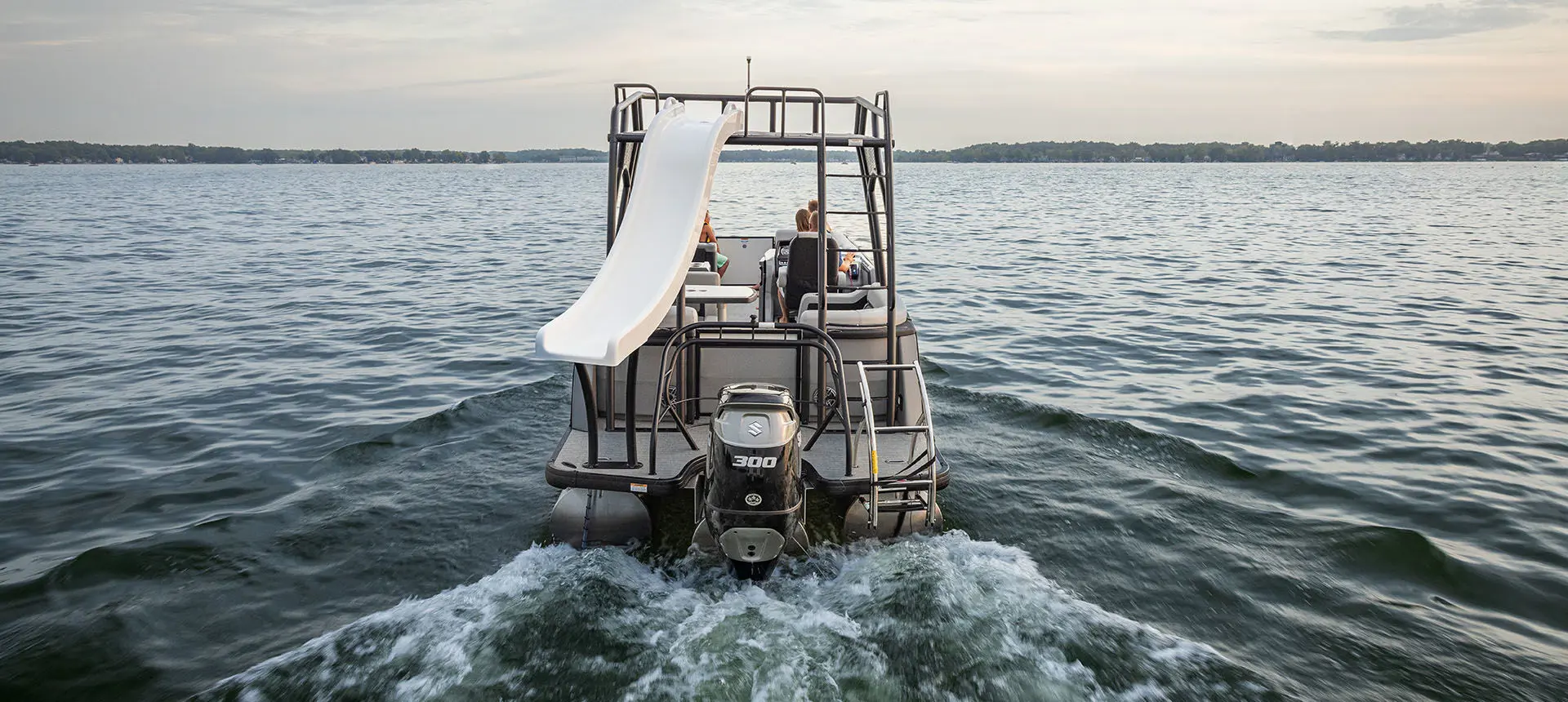 Stern focused view of a Godfrey AquaPatio Entertainment pontoon boat cruising on a lake.