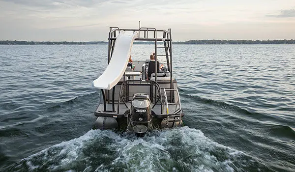 Stern focused view of a Godfrey AquaPatio Entertainment pontoon boat cruising on a lake.