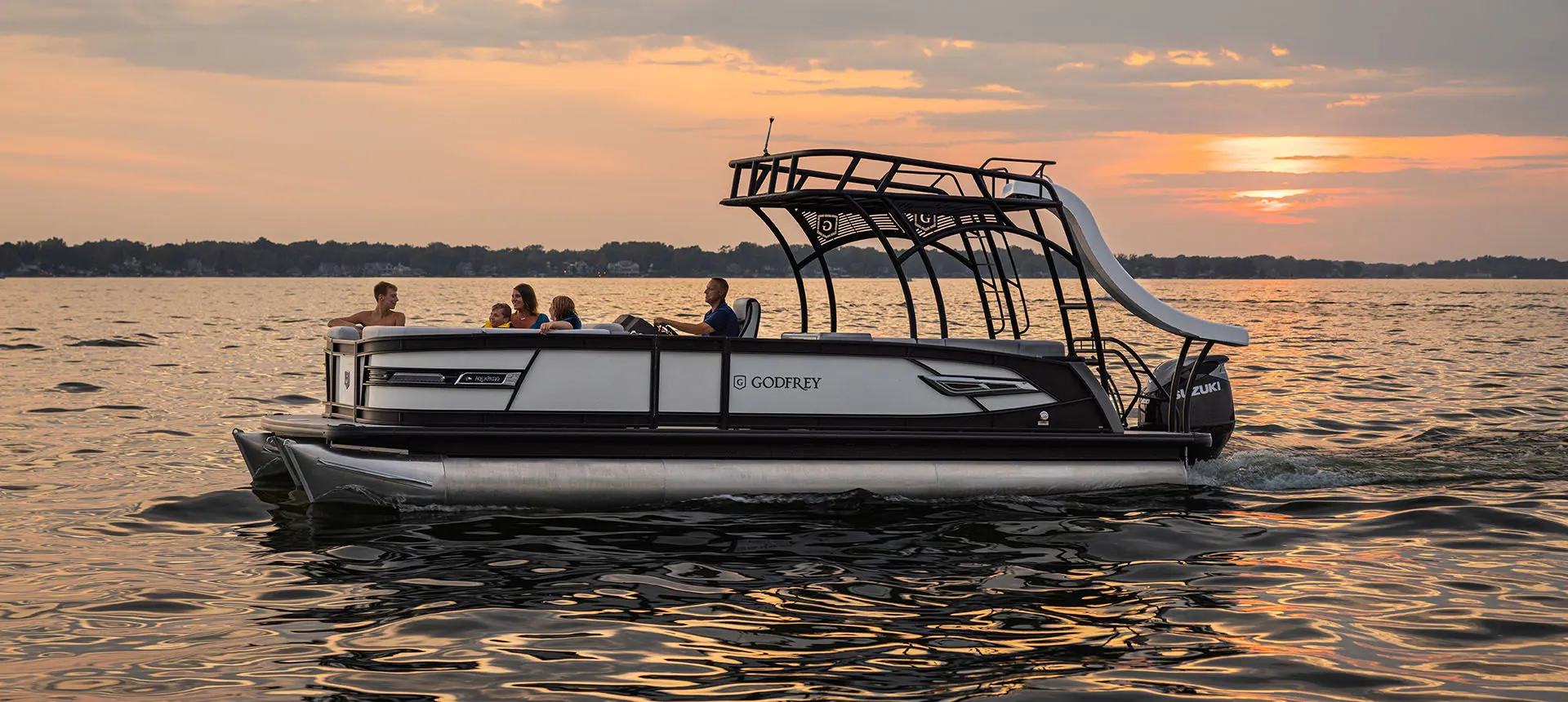 Side profile of a Godfrey AquaPatio Entertainment pontoon boat on a lake.