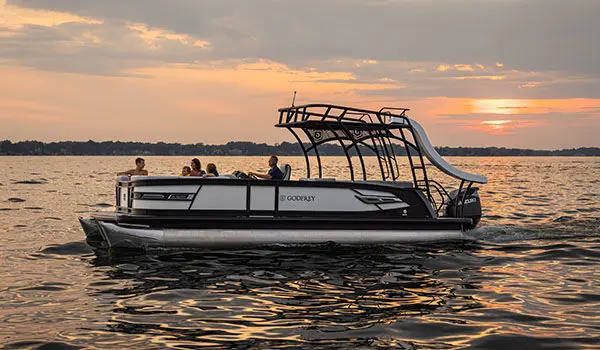 Side profile of a Godfrey AquaPatio Entertainment pontoon boat on a lake.