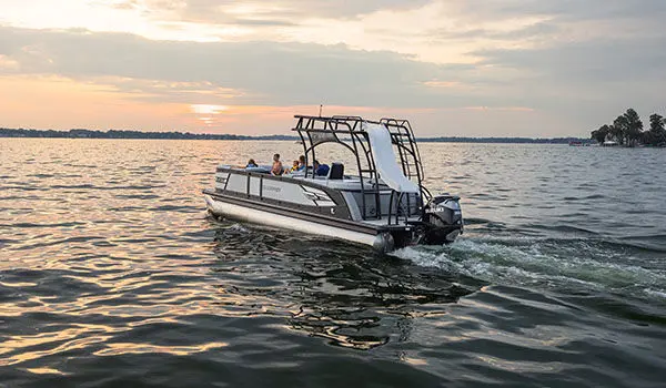 Far away view of a Godfrey AquaPatio Entertainment pontoon boat cruising on a lake.