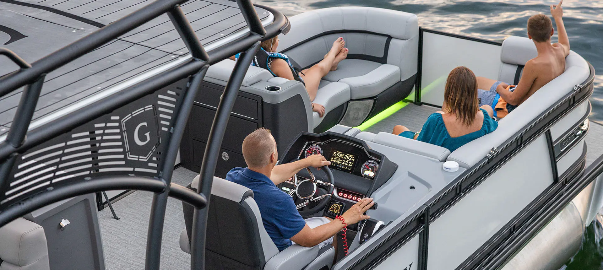 Aerial view of a man at the helm of a Godfrey AquaPatio Entertainment pontoon boat.