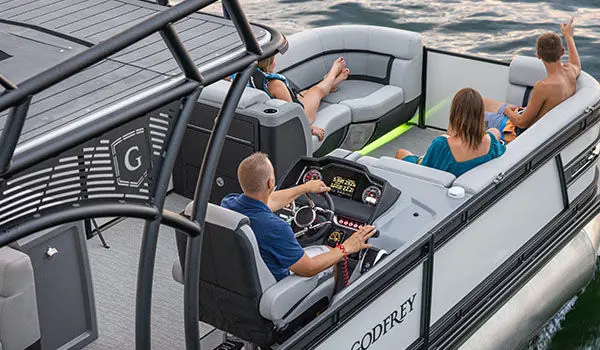Aerial view of a man at the helm of a Godfrey AquaPatio Entertainment pontoon boat.