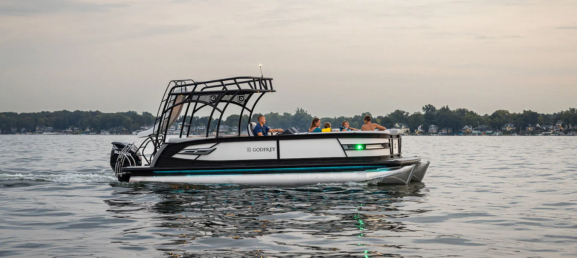 Side profile of a Godfrey AquaPatio Entertainment pontoon boat on a lake.