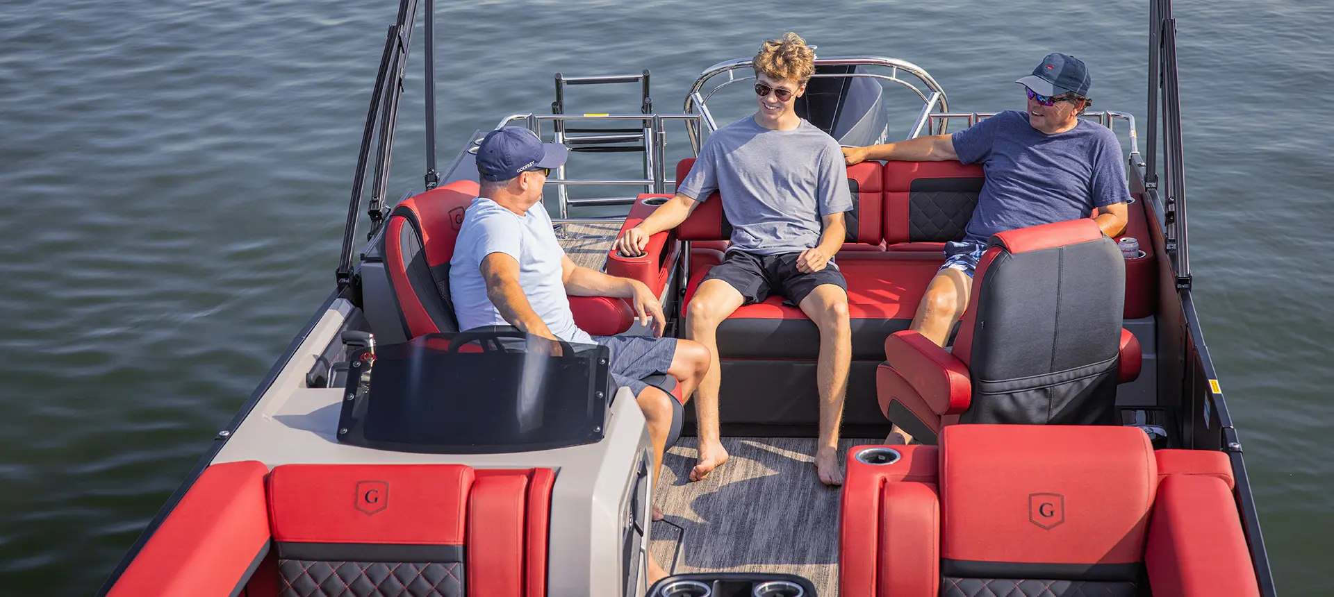 3 people relaxing on the stern lounge seating on a Godfrey AquaPatio Lounge pontoon boat.