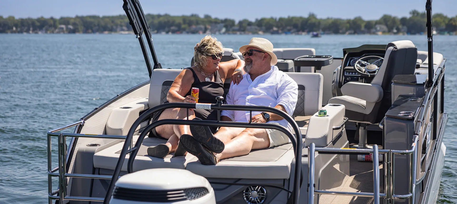 A couple chatting together from the stern lounge seat on a Godfrey AquaPatio Lounge pontoon boat.