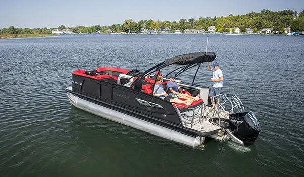 2 men sitting on the stern lounge seat while another man stands on the stern of a Godfrey AquaPatio Lounge pontoon boat.