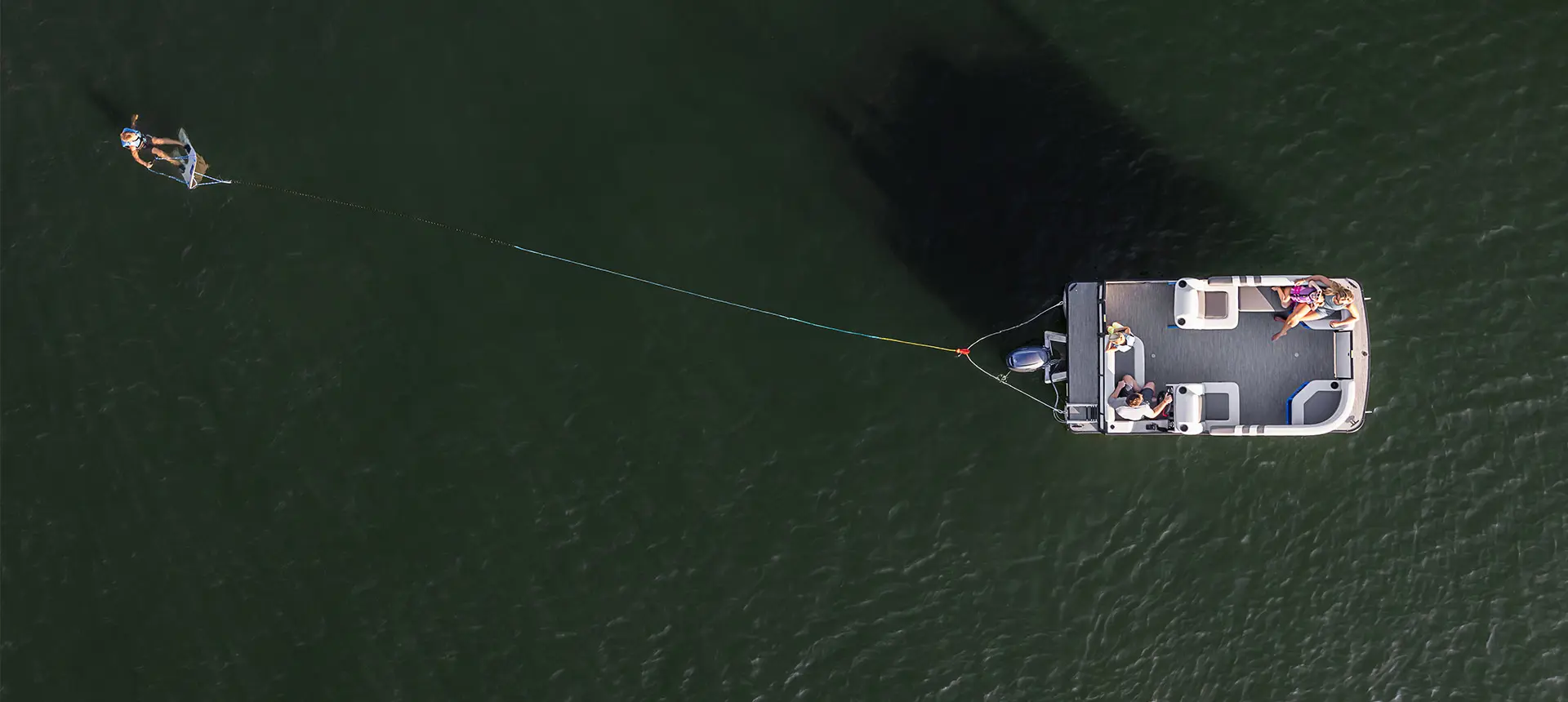 Aerial view of a Godfrey Mighty G pontoon boat pulling a wakeboarder.
