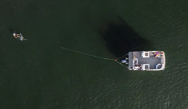 Aerial view of a Godfrey Mighty G pontoon boat pulling a wakeboarder.
