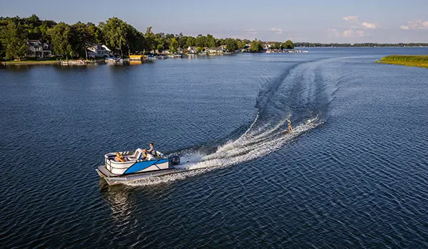 Side profile of a family on a Godfrey Mighty G Cruise pontoon boat while it pulled a wakeboarder.