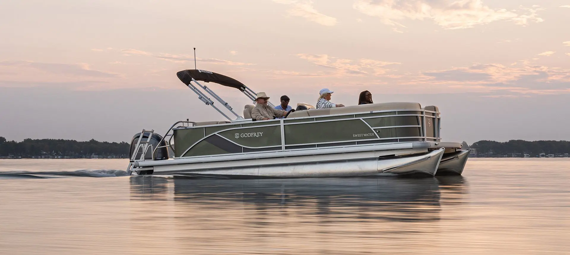 Side profile of a Godfrey Sweetwater Cruise pontoon boat floating on a lake.