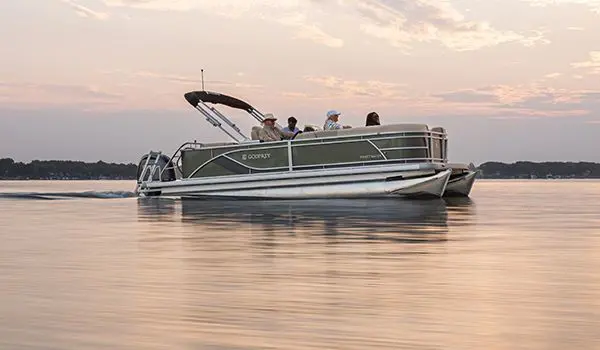 Side profile of a Godfrey Sweetwater Cruise pontoon boat floating on a lake.